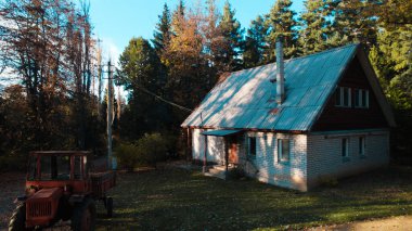 Ormandaki çiftçi evinin yanındaki eski kırmızı traktör.