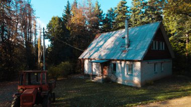 Ormandaki çiftçi evinin yanındaki eski kırmızı traktör.