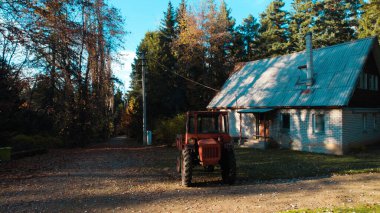 Ormandaki çiftçi evinin yanındaki eski kırmızı traktör.
