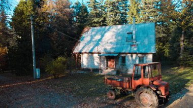 Ormandaki çiftçi evinin yanındaki eski kırmızı traktör.