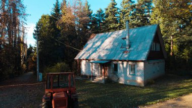 Ormandaki çiftçi evinin yanındaki eski kırmızı traktör.