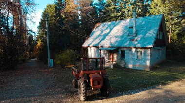 Ormandaki çiftçi evinin yanındaki eski kırmızı traktör.