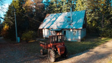 Ormandaki çiftçi evinin yanındaki eski kırmızı traktör.