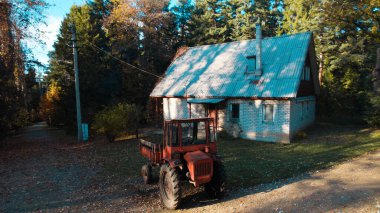 Ormandaki çiftçi evinin yanındaki eski kırmızı traktör.