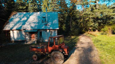 Ormandaki çiftçi evinin yanındaki eski kırmızı traktör.