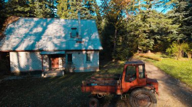 Ormandaki çiftçi evinin yanındaki eski kırmızı traktör.