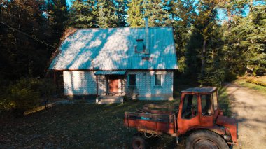 Ormandaki çiftçi evinin yanındaki eski kırmızı traktör.