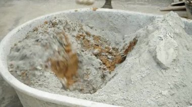Cement mixed with sand in a black bucket with a spade by a workingman