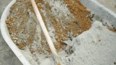 Cement mixed with sand in a black bucket with a spade by a workingman