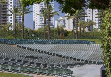 Sokak tribünleri, bir şehir caddesinde palmiye ağaçlarına monte edilmiş gri koltuklarla dolu. Park City Festivali 'nde yerler birbirinin üstünde yer alıyor. Boş sinema koltukları.