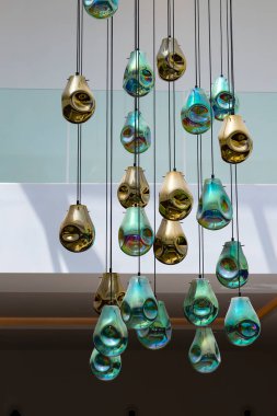 Tavan camları oturma odasının iç dekorasyonu. Tavandan sarkan cam kolye ışıklarının dikey görüntüsü. Uzun kablolarda, kablolarda, sıra sıra parlayan ampuller. Tavan lambaları.