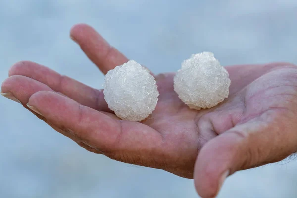 Salt crystals in the palms of your hands, close up, round cubes. Shallow depth of field, macro of white crystals of rock sea salt. Salt from the Dead Sea on the palm of hand. Crystallised Sea-salt