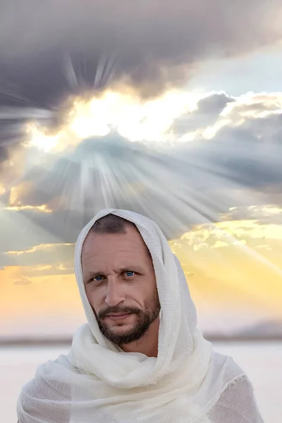 God in the rays of the sun light rays, bursting from the clouds on a sunset sky in the sand dunes. Spiritual religious background. Jesus Christ looking serious into camera and to you of Nazareth