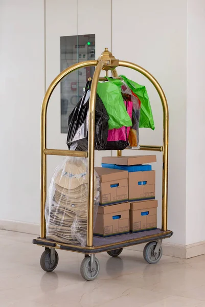 Luggage trolley cart packed with lots of things ready for the road trip. Many packages on hotel luggage cart. Trolley luggage at the hotel with a boxes stacked one above the other for transport.