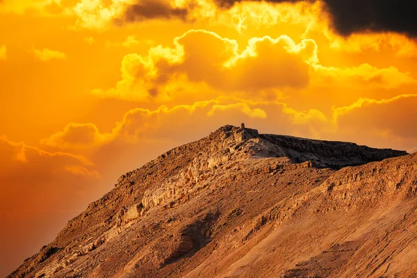 Dramatic evening gold sunset sky over mountain Sodom Gomorrah from Negev desert, Israel, Dead sea.  Sunset on a foggy mountains range Sodom with fluffy clouds. Sun shining on rocky landscape in hills