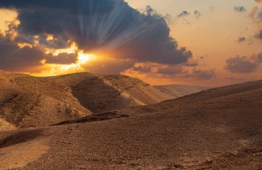 Sunset in the desert and sun rays spreading. Beautiful dramatic clouds on gold sky. Golden sand dunes in desert in Judean desert, Israel. Sunny sky over cliffs, large salt mountains Sodom and Gomorrah clipart