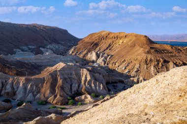 Sodom Dağı Gomora. Mavi gökyüzünde güzel bulutlar. İsrail 'in Judean çölündeki altın kum tepeleri. Kayalıkların üzerinde güneşli bir gökyüzü, Ölü Deniz 'de büyük bir tuz dağı. Nahal Dragot Wadi 'nin kurumuş nehir yatağı