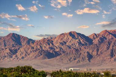 Dağlar Eilat sırtında. İsrail 'deki Kızıl Deniz Körfezi yakınlarındaki dağlardan yürü. Dağ sırası ve açık gün gökyüzü. İnanılmaz güzel bir çöl, palmiye ağacı, bulutlar ve mavi gökyüzü.. 
