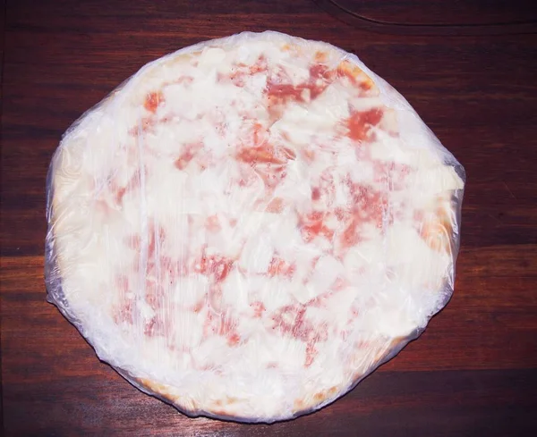 Gefrostete Handelsübliche Pizza Einer Plastikverpackung Einer Küchenarbeitsplatte Mit Holzhintergrund — Stockfoto
