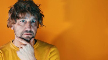 Gündelik kıyafetler giyen genç İspanyol adam şüphe üzerine yoğunlaşmıştı parmakları çenesinde kameraya bakarken turuncu arka plan komplo konseptini merak ediyordu. .