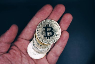 Hand of an old man holding bitcoins .