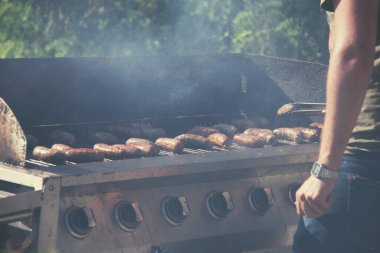 Adamın biri, yaz akşamı BBC 'de verandada yemek pişiriyor.