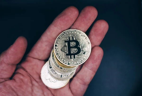 Hand of an old man holding bitcoins .