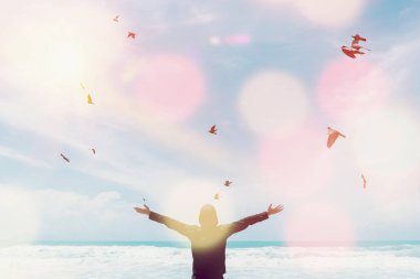 Sahilde ve adada kuşların soyut arka planda uçtuğu mavi gökyüzünde insan elini kaldırır. Özgürlük ve seyahat macera konsepti. Klasik ton filtresi renk biçimi.