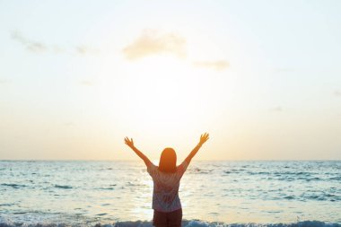 Sahilde ve adada, günbatımında gökyüzünde yükselen kadın mekânını kopyalayın. Özgürlük ve seyahat macera konsepti. Klasik ton filtre efekti renk biçimi.