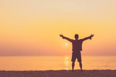 Sahilde ve adada insanın günbatımında gökyüzüne yükselişini kopyalayın. Özgürlük ve seyahat macera konsepti. Klasik ton filtre efekti renk biçimi.