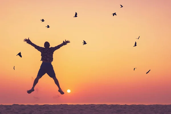 Günbatımında Gökyüzünde Uçan Kuşlarla Tropikal Plajda Zıplayan Mutlu Bir Adam — Stok fotoğraf