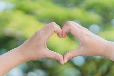 Doğada kadın eli kalp şekli Bokeh güneş ışığı parıltısı ve bulanık yaprak soyut arka plan. Mutlu aşk ve özgürlük kavramını kopyala. Klasik ton filtresi renk biçimi.