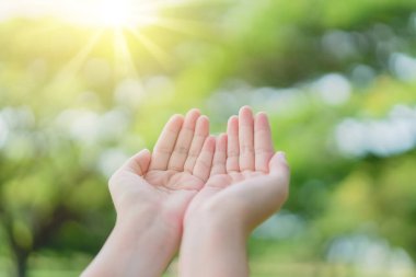 Kadın gün batımına kadar elini açık tut gökyüzü ve yeşil yaprak bokeh güneş ışığı soyut arkaplan. Klasik ton filtre efekti renk biçimi.