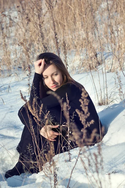 Beautiful girl sitting in snow field — Stock Photo, Image