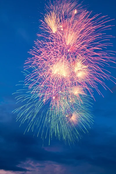 Fuegos artificiales coloridos sobre el fondo azul nublado del cielo — Foto de Stock