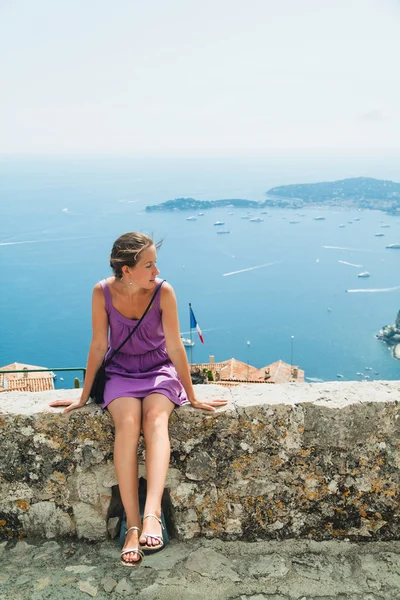 Young girl sitting in front of the azure mediterranean sea in french city Eze Village. France, cote' d'azur Europe. — Stock Photo, Image