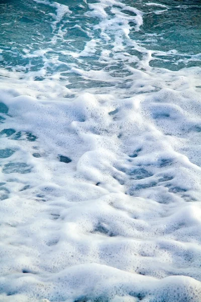 Azure sea waves. Clear blue water with white foam. Pebbles on th — Stock Photo, Image