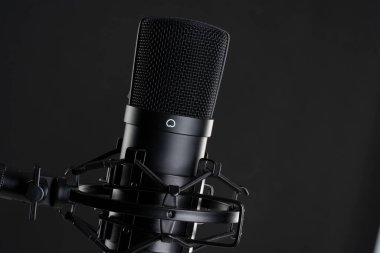 Close up image of professional studio microphone on the black background during singing recording clipart