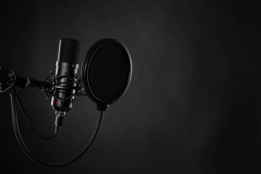 Podcast için ses kaydı sırasında stüdyoda siyah arkaplanda siyah profesyonel mikrofon