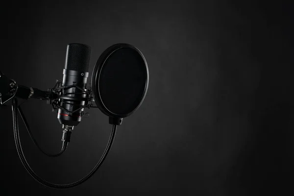 Podcast için ses kaydı sırasında stüdyoda siyah arkaplanda siyah profesyonel mikrofon