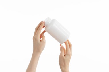 Kadının elinde beyaz bir şişe ilaç hapı, vitamin ya da takviye bezi tutarken ki görüntüsünü kapat..