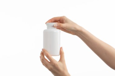 Kadının elinde beyaz bir şişe ilaç hapı, vitamin ya da takviye bezi tutarken ki görüntüsünü kapat..