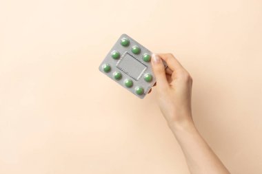 Kadın elinin bej arka planda izole edilmiş uyuşturucu kabarcıklarını tutarken yakın plan görüntüsü