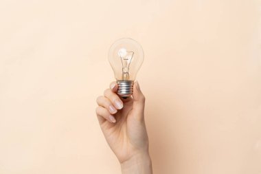 Bej arka planda izole edilmiş ampullü Wonas elinin yakın plan görüntüsü