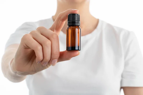 Kadının elinde küçük bir kavanoz yağ ya da başka bir vitamin damlası ya da takviye bezi tutarken çekilmiş yakın bir fotoğrafı. Beyaz arkaplanda izole.