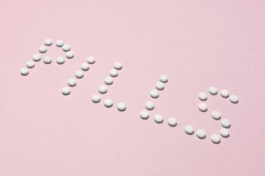 Arka planda küçük beyaz ağrı kesiciler tarafından yapılan haplar.