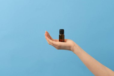 Bir kadın eli, arka planda bir kavanoz sıvı, saç yağı ya da takviye malzemesi tutuyor. temel yağlar için etiket kabı yok