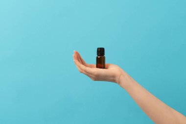 Bir kadın eli, arka planda bir kavanoz sıvı, saç yağı ya da takviye malzemesi tutuyor. temel yağlar için etiket kabı yok