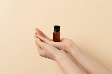 Kadın elinde bej arka planda bir kavanoz sıvı tutuyor.