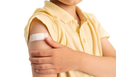 Kolunda yara bandı olan küçük bir çocuk. 